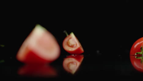 Saftige-Rote-Tomatenscheiben-Fallen-In-4-Teile-Glas-Mit-Wasserspritzern-In-Zeitlupe-Auf-Dunklem-Hintergrund